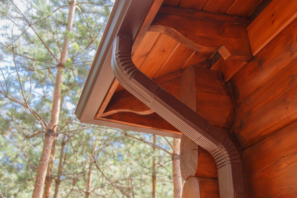 Brown gutters installed on red wood home